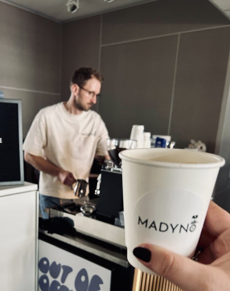 Gast hält einen gebrandeten Madynio-Becher